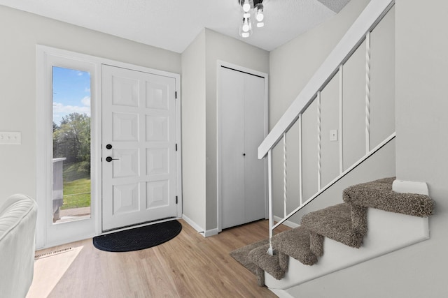 entrance foyer with wood finished floors, stairway, and baseboards