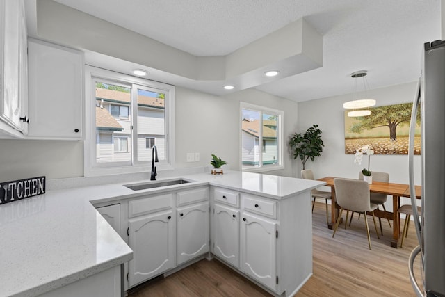 kitchen with a sink, white cabinetry, light wood-type flooring, plenty of natural light, and recessed lighting