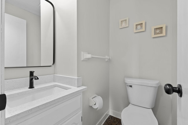 bathroom featuring baseboards, toilet, and vanity