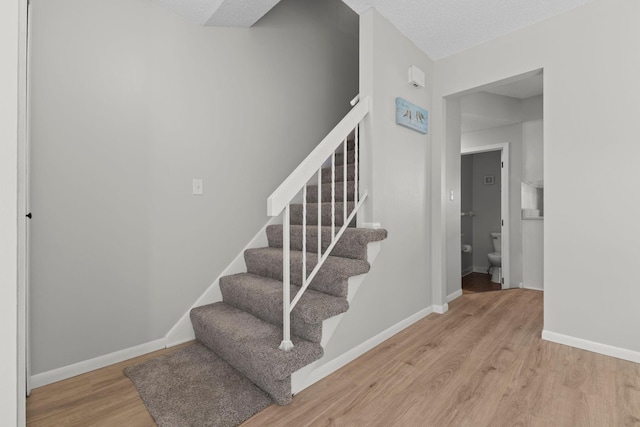 stairway featuring wood finished floors and baseboards