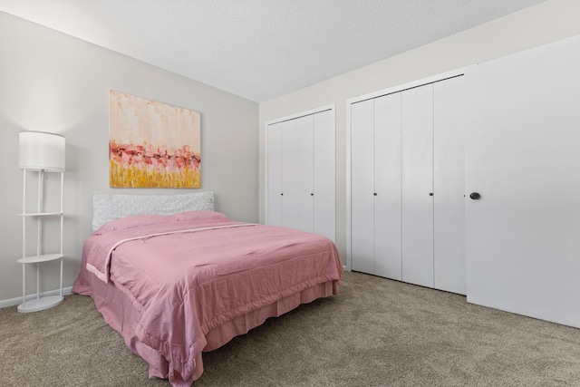 bedroom with carpet, two closets, and a textured ceiling