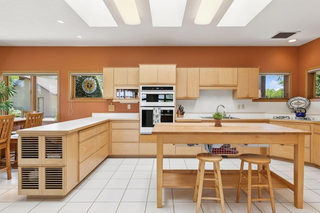 32875 Stanton Trl, Cannon Falls, MN 55009 - kitchen with light brown cabinetry, a skylight, double oven, light countertops, and recessed lighting
