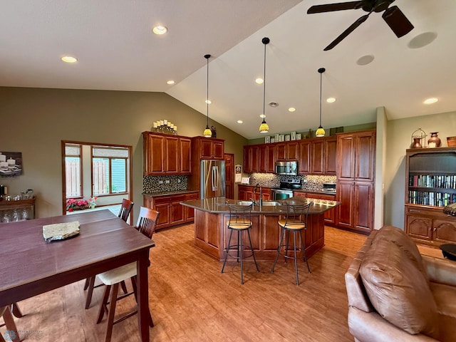 3823 43rd Ave S, Moorhead, MN 56560 - kitchen featuring appliances with stainless steel finishes, vaulted ceiling, tasteful backsplash, ceiling fan, and a breakfast bar