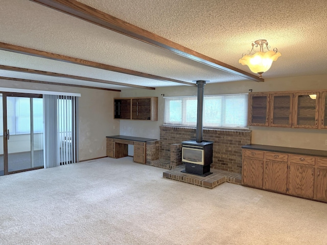 1611 Graydon Ave, Brainerd, MN 56401 - unfurnished living room with a textured ceiling, a wood stove, light carpet, and beam ceiling