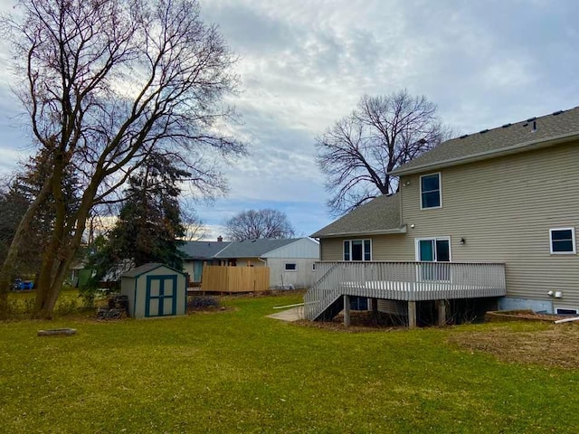 back of property with a storage unit, a deck, an outdoor structure, a yard, and a shingled roof