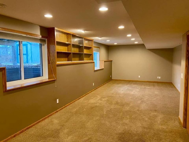 below grade area featuring light colored carpet, recessed lighting, and baseboards