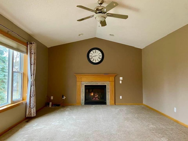 unfurnished living room with ceiling fan, light colored carpet, a lit fireplace, baseboards, and vaulted ceiling
