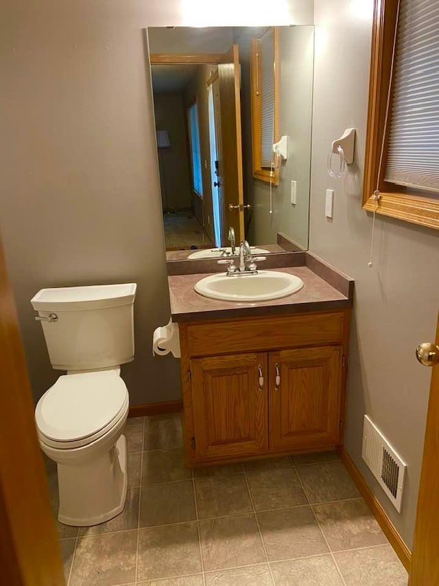 half bath featuring toilet, vanity, and tile patterned floors