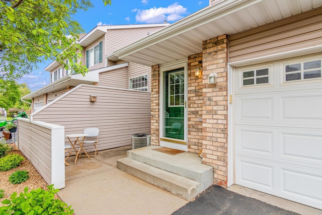 entrance to property featuring central air condition unit and a garage