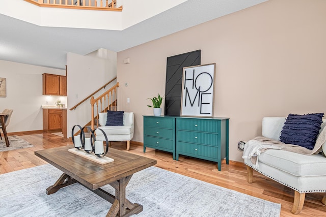 living room featuring light wood-type flooring, stairway, and baseboards