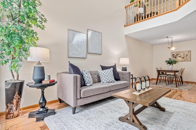 living area with wood finished floors, baseboards, and a high ceiling