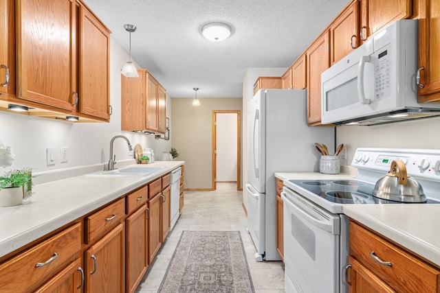 kitchen featuring white appliances, a sink, brown cabinets, light countertops, and decorative light fixtures