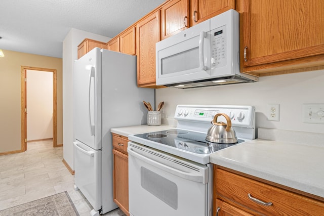 kitchen with white appliances, light countertops, and brown cabinets
