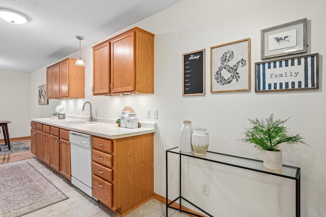 kitchen with dishwasher, a sink, light countertops, brown cabinets, and hanging light fixtures