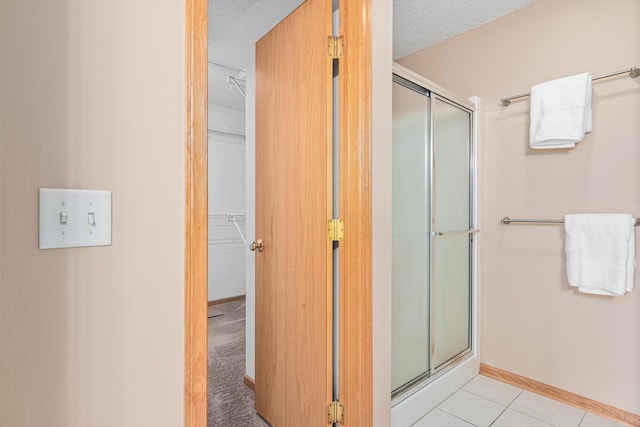 bathroom with a shower stall, baseboards, and tile patterned floors