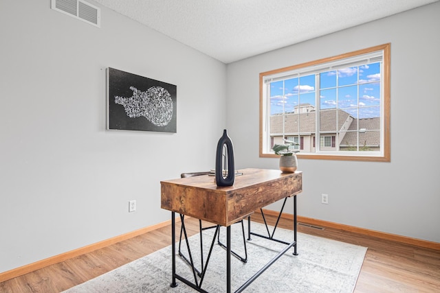 office with wood finished floors, baseboards, and a textured ceiling
