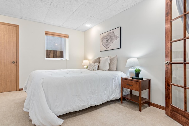 carpeted bedroom featuring a paneled ceiling and baseboards