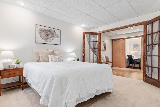 carpeted bedroom featuring recessed lighting and a drop ceiling