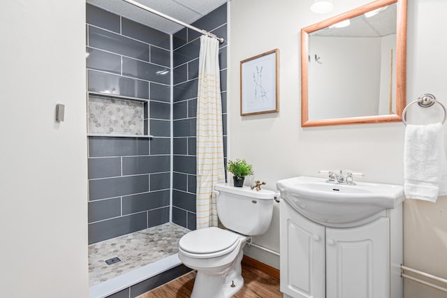 full bathroom with wood finished floors, a shower stall, vanity, toilet, and baseboards