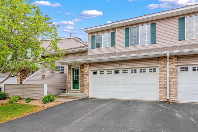 view of property featuring an attached garage, asphalt driveway, and stone siding