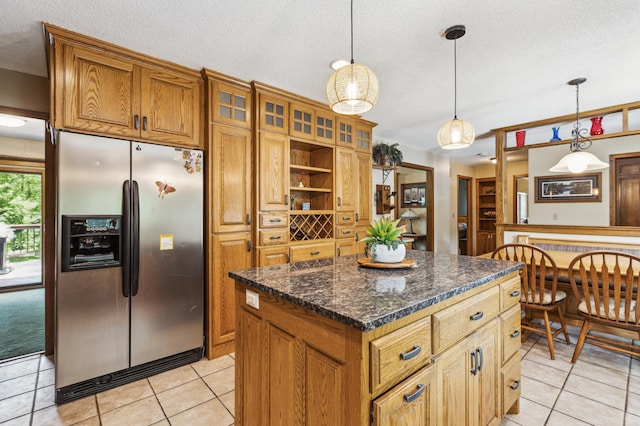 5651 164th Ln NW, Ramsey, MN 55303 - kitchen with stainless steel fridge with ice dispenser, a textured ceiling, brown cabinetry, a kitchen island, and light tile patterned flooring