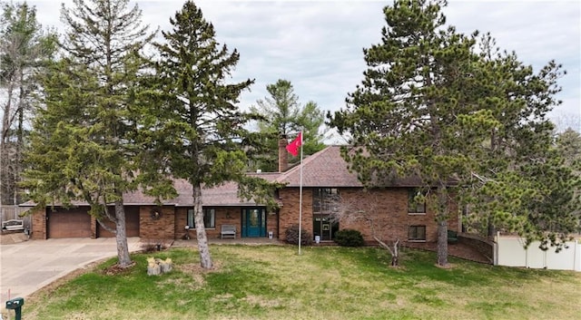 view of front of home featuring driveway, brick siding, a chimney, and an attached garage