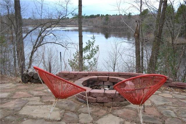 view of patio featuring a fire pit, a water view, and a view of trees