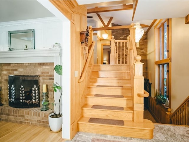 stairs featuring wood finished floors, a fireplace, and a chandelier