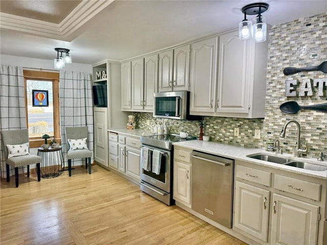 kitchen featuring appliances with stainless steel finishes, a sink, light countertops, and backsplash