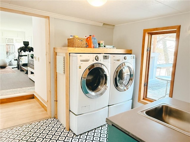 laundry area with separate washer and dryer, crown molding, and light wood-style flooring