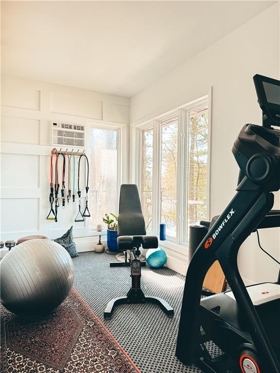 workout area featuring healthy amount of natural light, carpet floors, and a wall mounted air conditioner