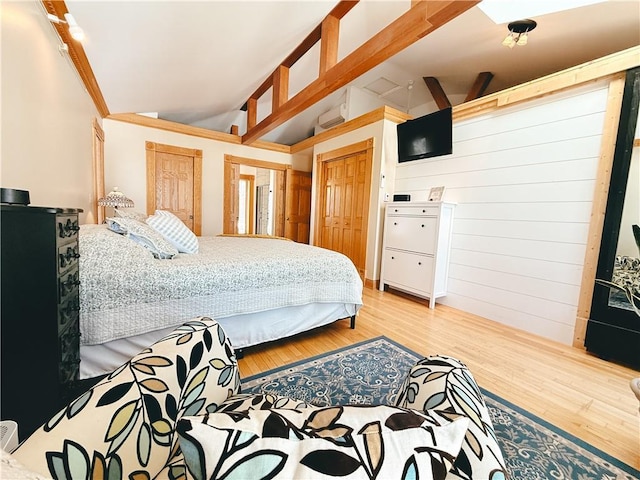 bedroom featuring lofted ceiling, wood finished floors, and two closets