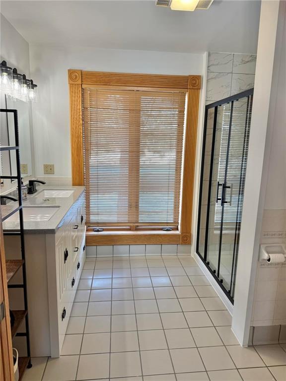 full bath with a stall shower, tile patterned flooring, and double vanity