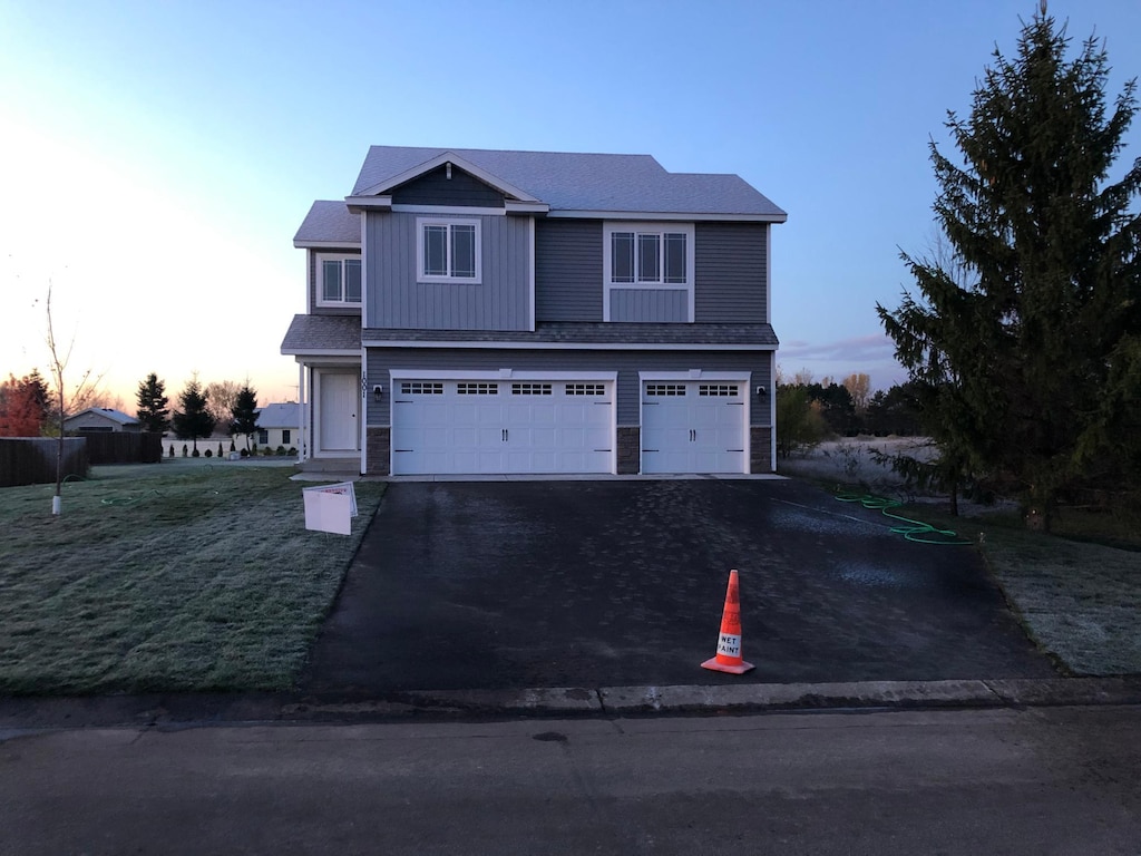 traditional home with an attached garage, driveway, and a shingled roof
