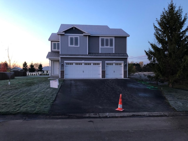 traditional home with an attached garage, driveway, and a shingled roof