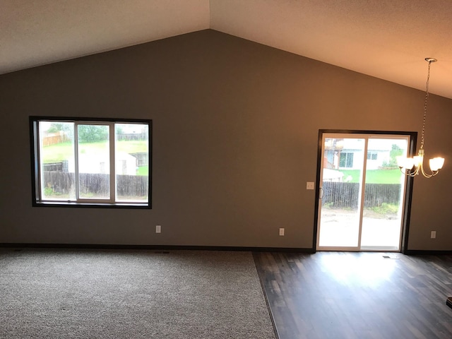 empty room featuring vaulted ceiling, a chandelier, dark wood-style floors, baseboards, and dark carpet