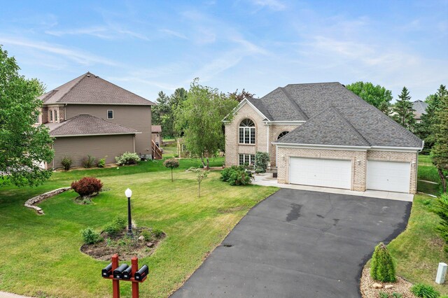 2001 Stonepine Ave, Hudson, WI 54016 - view of front of home featuring an attached garage, a front lawn, asphalt driveway, and brick siding