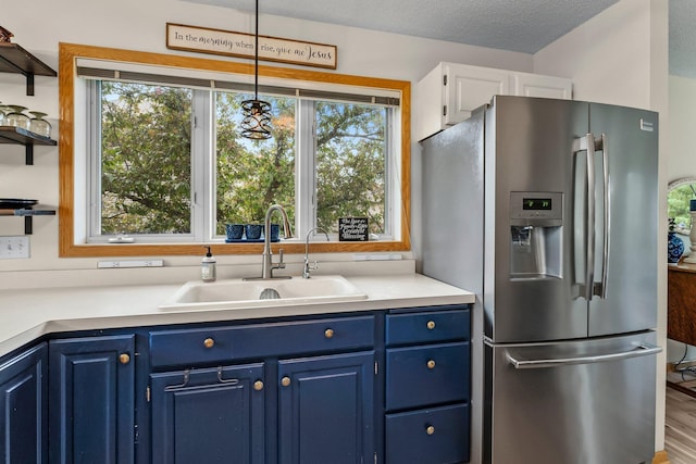 2001 Stonepine Ave, Hudson, WI 54016 - kitchen featuring stainless steel fridge, blue cabinets, a sink, and healthy amount of natural light