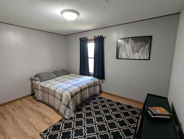 bedroom with light wood-style flooring, baseboards, and a textured ceiling