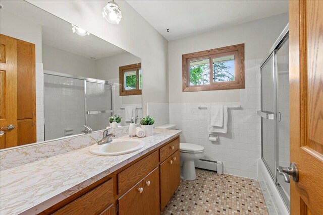 5935 County Road 11, Independence, MN 55359 - bathroom featuring a baseboard radiator, vanity, toilet, tile walls, and enclosed tub / shower combo