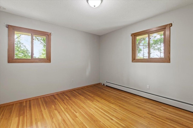 5935 County Road 11, Independence, MN 55359 - unfurnished room featuring a baseboard radiator, plenty of natural light, light wood finished floors, baseboards, and a textured ceiling
