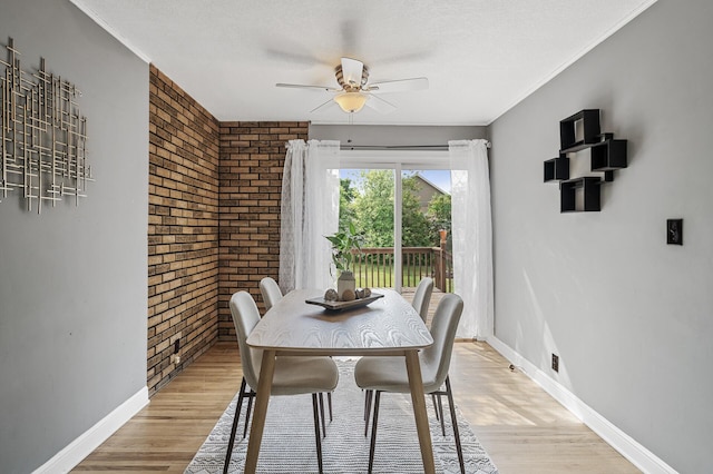 dining room featuring brick wall, a ceiling fan, baseboards, and light wood-type flooring