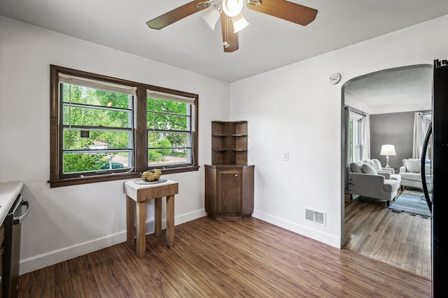 interior space with baseboards, wood finished floors, a ceiling fan, and arched walkways