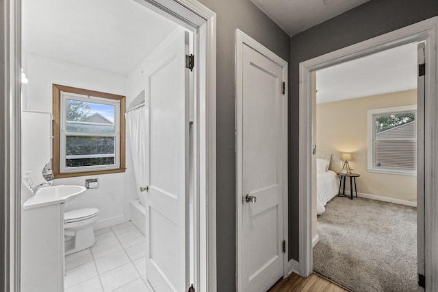 full bath with toilet, shower / bath combo with shower curtain, a sink, and baseboards
