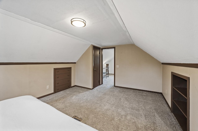 unfurnished bedroom featuring carpet floors, vaulted ceiling, baseboards, and a textured ceiling