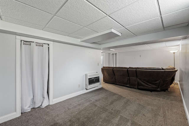 finished basement with heating unit, a drop ceiling, carpet, and baseboards