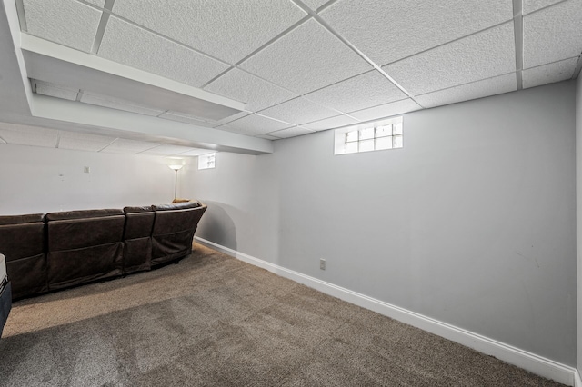 below grade area with carpet flooring, a drop ceiling, and baseboards