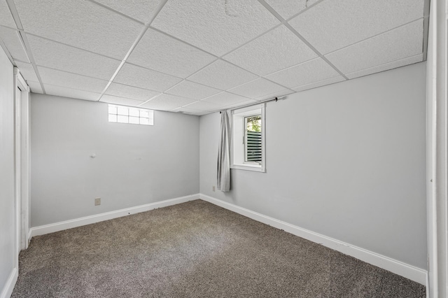 below grade area featuring a paneled ceiling, carpet, and baseboards