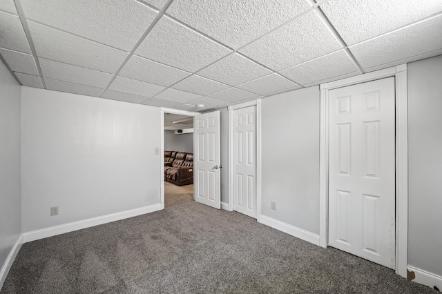 finished basement with carpet flooring, a drop ceiling, and baseboards