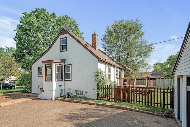 back of property featuring a chimney, fence, and stucco siding